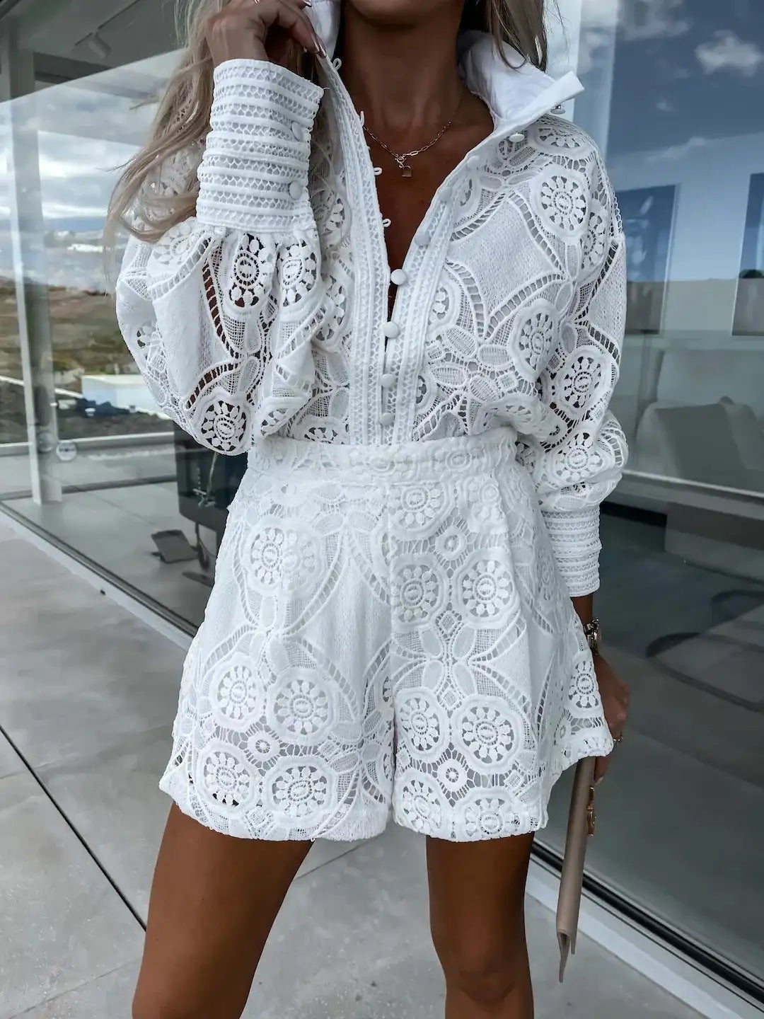 Conjunto casual feminino de duas peças com blusa de gola dobrável com botões e detalhes em renda vazada e shorts de cintura alta com bolsos.